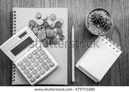 note book and coin on the wooden table with black and white color 