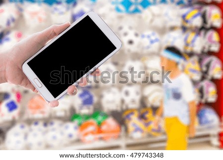 Man use mobile phone, blur image of sports shop as background.
