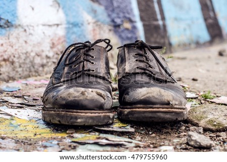 Conceptual shooting of homeless man dirty shoes left on the street Royalty-Free Stock Photo #479755960