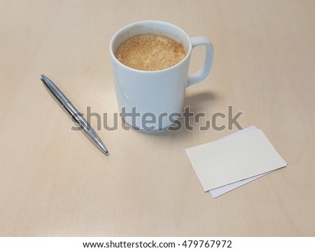 Morning cup of coffe with a silver pen