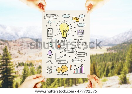 Hands holding paper with business sketch on landscape background. Idea concept
