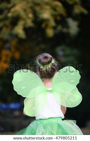 Happy little girl in a green fairy costume with wings