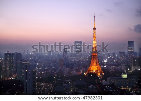 Light up Tokyo Tower during sunset surrounded by other buildings in Tokyo, Japan