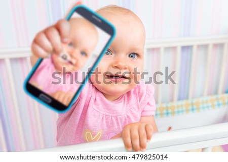Baby girl taking selfie with a cell phone camera