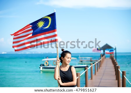 Girl on pier on Sabah island with Malaysian flag