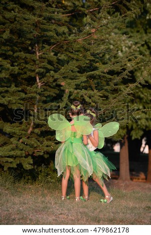 Two girls in a green fairy costume with wings