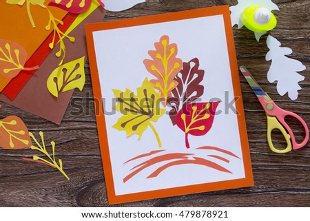 Autumn leaves of colored paper on a wooden background. Sheets of paper crafts for kids. Children's art project.