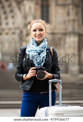 Urban portrait of young caucasian woman traveller with photo camera 
