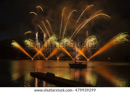 Ignis Brunensis green silver and gold colored firework resembling aster flower reflecting on dam water surface. Long exposure night graphical photography using creative tilt effect by tilt-shift lens.