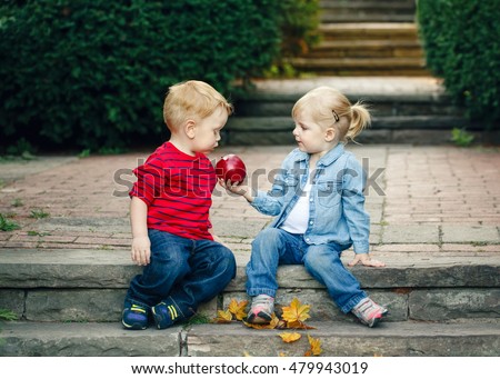 Group portrait of two white Caucasian cute adorable funny children toddlers sitting together sharing apple food, love friendship childhood concept, best friends forever Royalty-Free Stock Photo #479943019