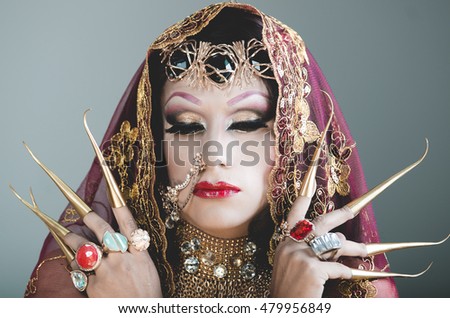 Headshot woman dressed in traditional hindu clothing, heavily decorated in gold and elegant veil, extremely long fingernails, posing artistically for camera, hindusim dancer concept