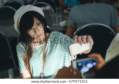 Charming Asian girl in casual wear taking selfie photo