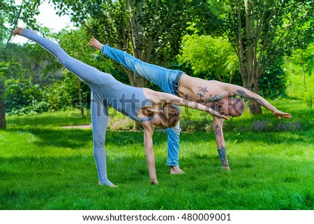 Man and woman yogi doing various yoga poses in a pair. Healthy yoga lifestyle. Yoga in the summer park, outdoor.