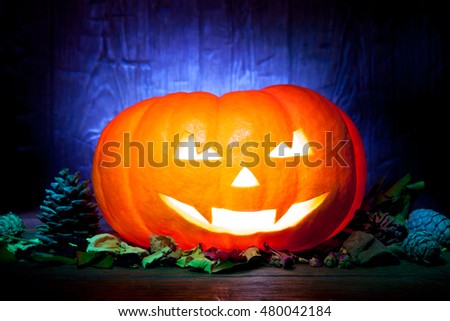 Scary Halloween pumpkin on a old blue wooden background. Scary glowing faces trick or treat