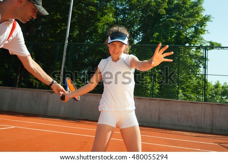 Young talent learning technique with tennis instructor on clay court