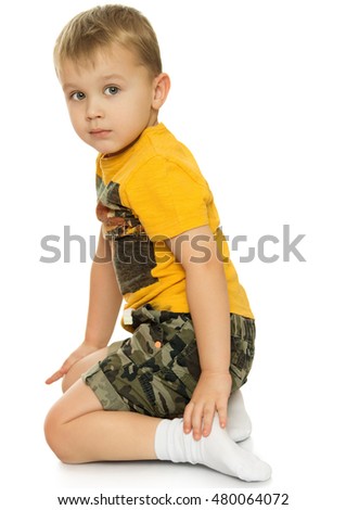  Little blond boy in a yellow t-shirt and shorts is sitting on the floor- Isolated on white background