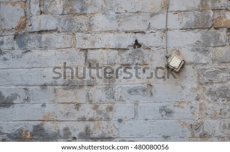 Aged worn light switcher on the background of an old textured faded brick wall.