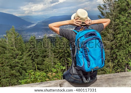 Happy tourist girl backpack sitting in the Austrian Alps mountain and enjoying summer and nature. View from Villach alpine road (Austria). Freedom. Relax. Healthy lifestyle. 