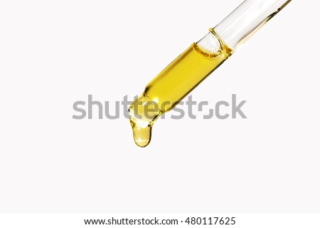 transparent glass pipette with a Golden liquid dripping Royalty-Free Stock Photo #480117625