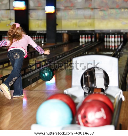 Child girl in with bowling ball learn game.
