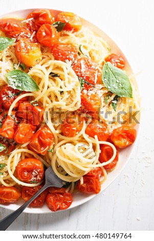 spaghetti with roasted cherry tomato and fresh basil in a white plate
