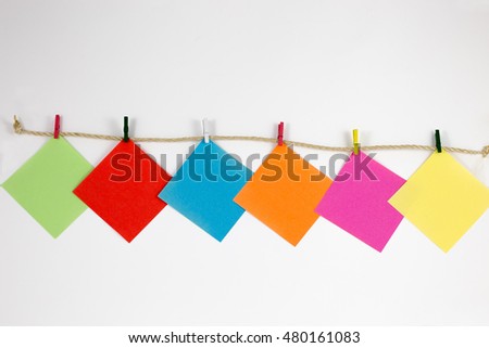 Post-it notes with small colored pegs in a rope in white background