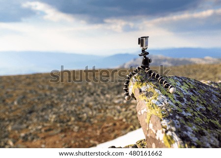 compact action camera mounted on a flexible tripod gorilla on rock in mountains