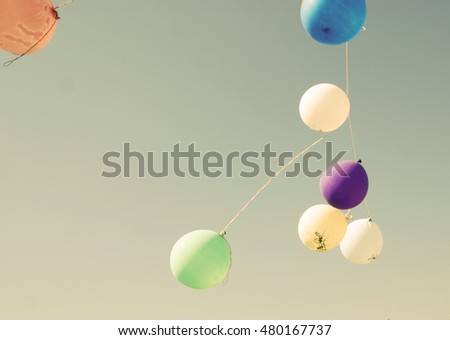 Colored balloons on a rope against the blue sky develop in the air. Vintage picture with balloons