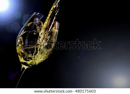 glass with white wine on black background