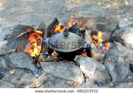 Cooking food in a cast iron pot over an open fire, hiking. Tourist lunch, cooking food on fire.