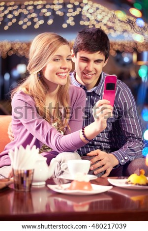 Girl making photo with her boyfriend in cafe