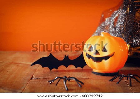 Halloween holiday concept. Witch hat next to cute pumpkin and bat on wooden table