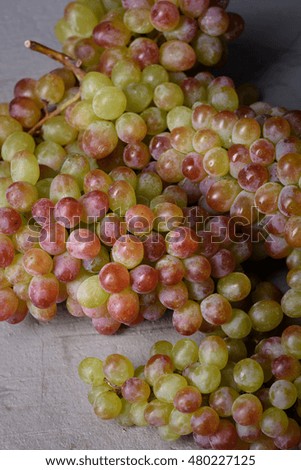 Bunch of grapes over grey background, fresh ripe fruits close up.