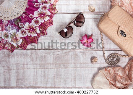 Fashion women accessories. Luxury handmade snakeskin (python) handbag, sunglasses and silk scarf. Top view, flat lay, light wooden  background. Free/empty space for text.