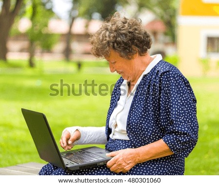 Old woman typing with her broken arm on her laptop to order and shop from the internet.