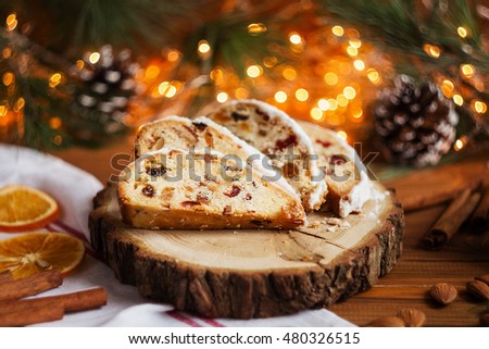 Slices of stollen on festive rustic wooden background with cchristmas light bokeh. Shallow focus