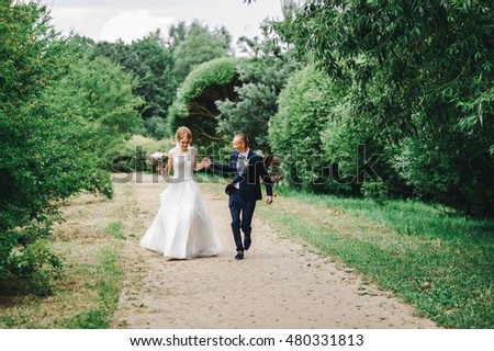 Bride and groom running and park and holding hands