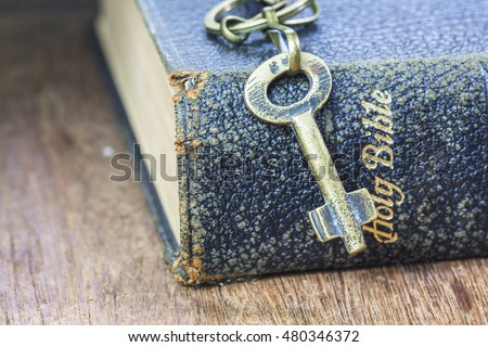 metal key with old book on brown wooden background, copy space, concept
