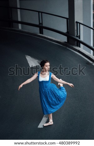 Beautiful girl in ballet shoes posing on concrete