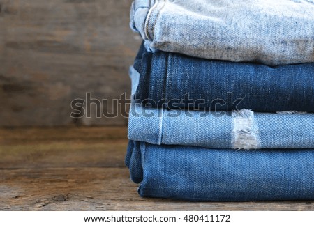 Fashionable and stylish clothes - a lot of different blue jeans closeup on wooden background