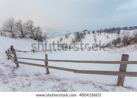 Rural alpine winter landscape with fence and path, serene blue sky