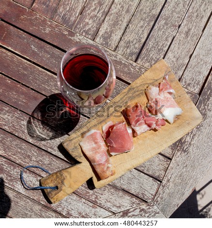 Platter of sliced meat and a glass of red wine