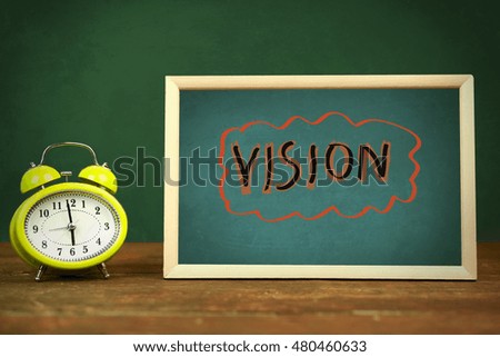 Vision  text on board and clock on wooden table