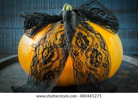 Idea homemade decorating for Halloween. Lacy black ribbon on the pumpkin. The original design in the style of Halloween. Tinted photo