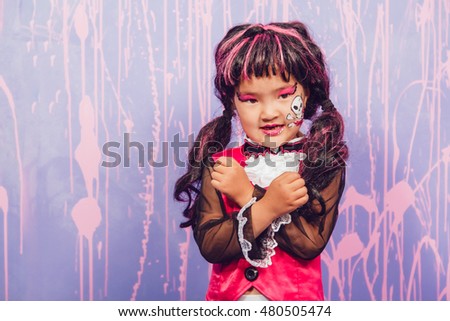 Girl in witch costume stands on a purple background