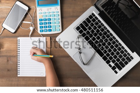 Office desk table with laptop, calculator, smartphone, pencil and notebook.Flat lay photo.Top view and kid hand working on desk table.