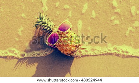 Funny pineapple in sunglasses on the beach.