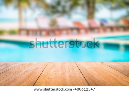 Image of wood table in front of swimming pool blur background. Brown wooden desk empty counter front view of the poolside on beautiful beach resort and outdoor spa. Royalty-Free Stock Photo #480612547