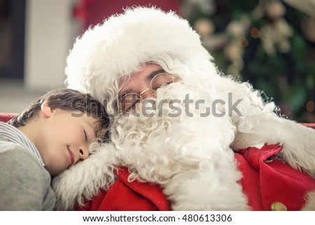 Santa Claus and young boy sleeping on a couch at home