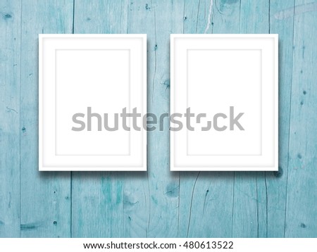 Close-up of two blank picture frames on aqua weathered wooden boards background